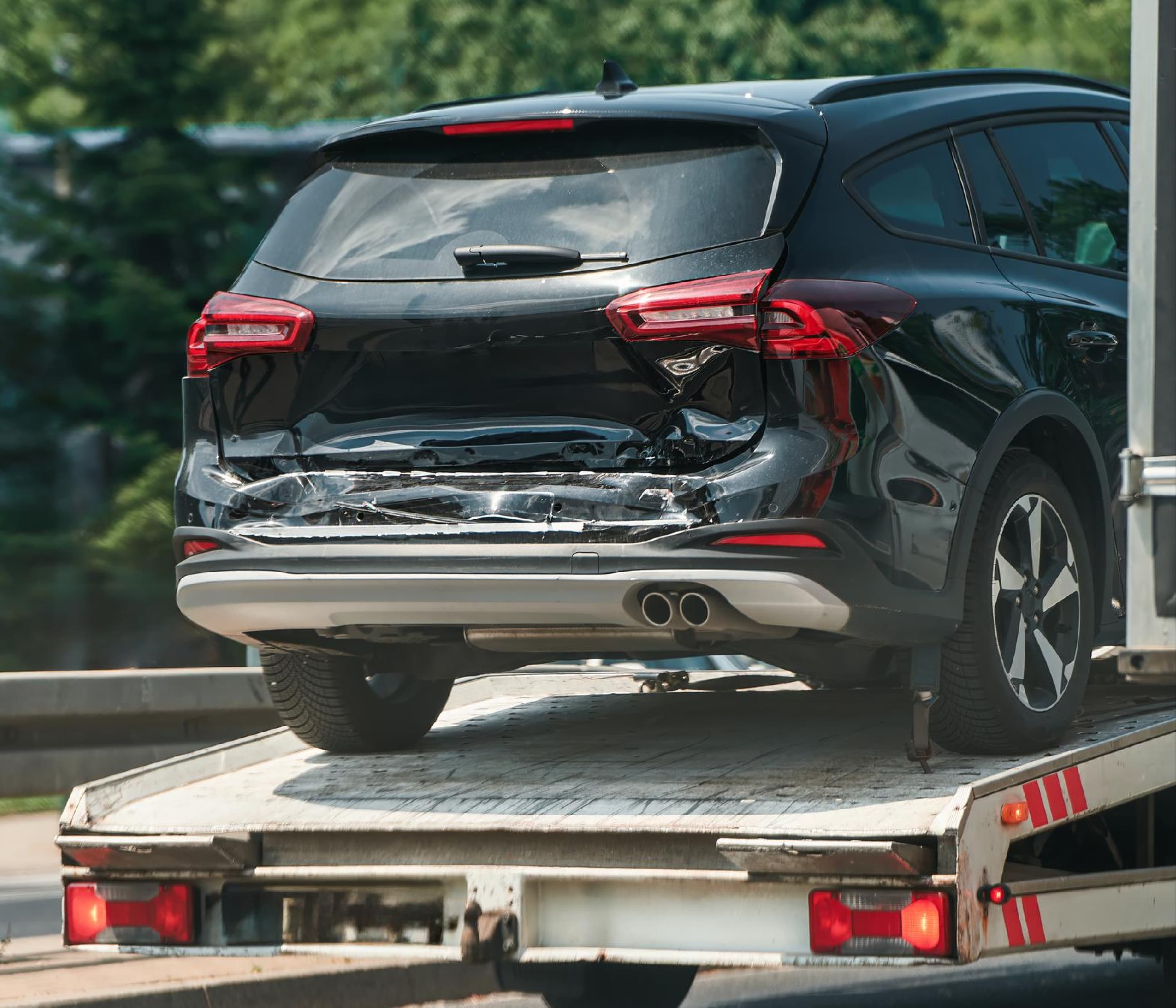 Rear-damaged SUV loaded on a tow truck